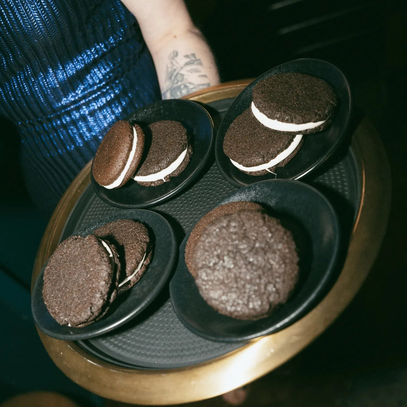 Person holding a tray with corporate cookie gifts at a cocktail bar