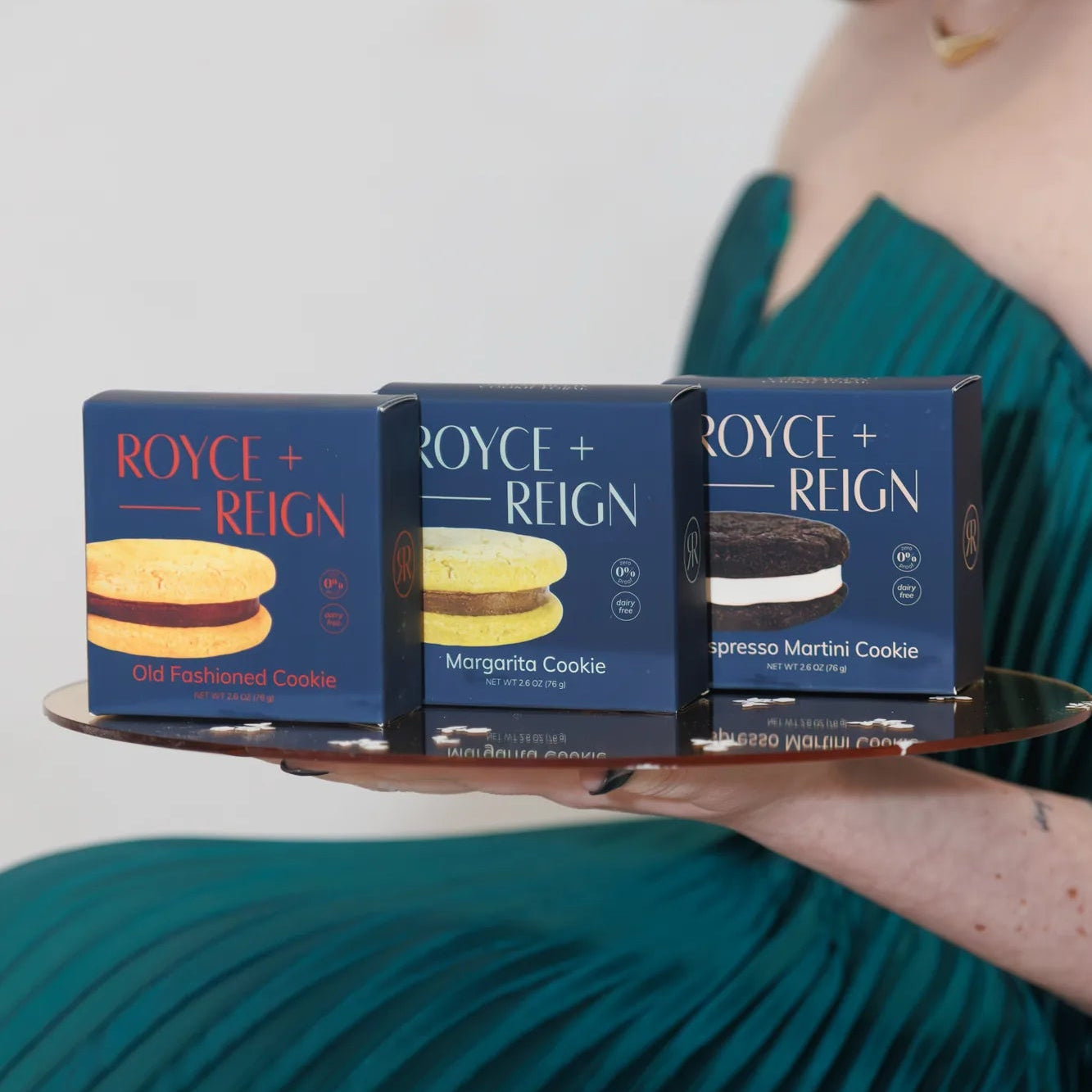 Founder holding a tray with three boxes of Royce + Reign cookies.