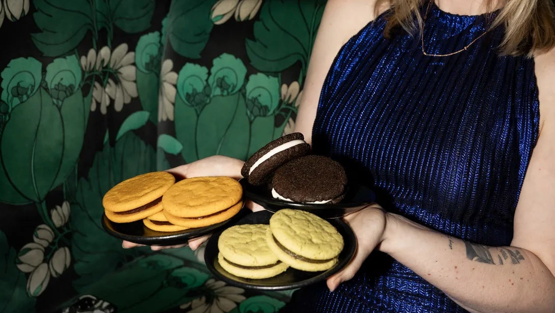 Founder of Royce+Reign holding three plates of cookies showcasing the three conctail-inpired, zero-proof event favors that Royce+Reign offers in their Cookie Flight bundle.